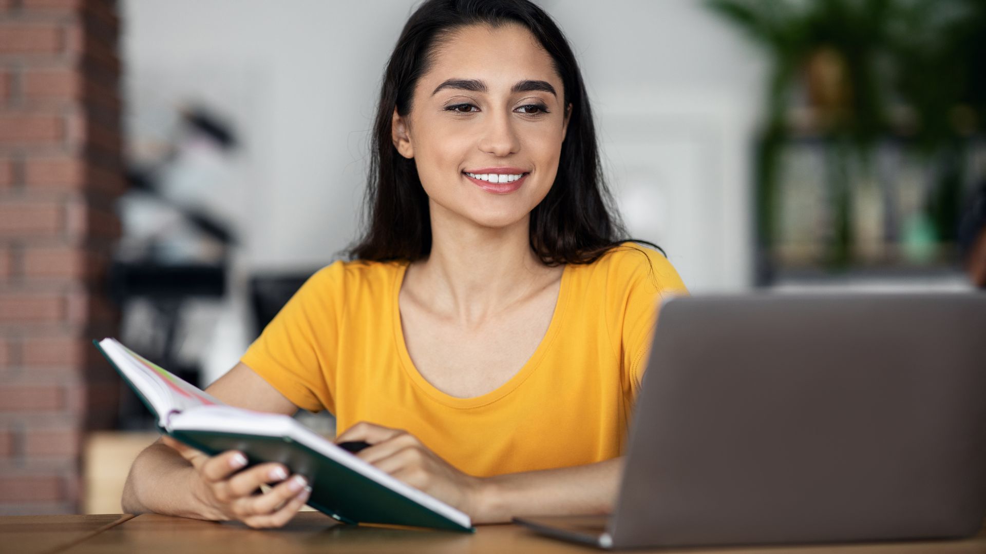 Femme souriante travaillant sur ordinateur et prenant des notes