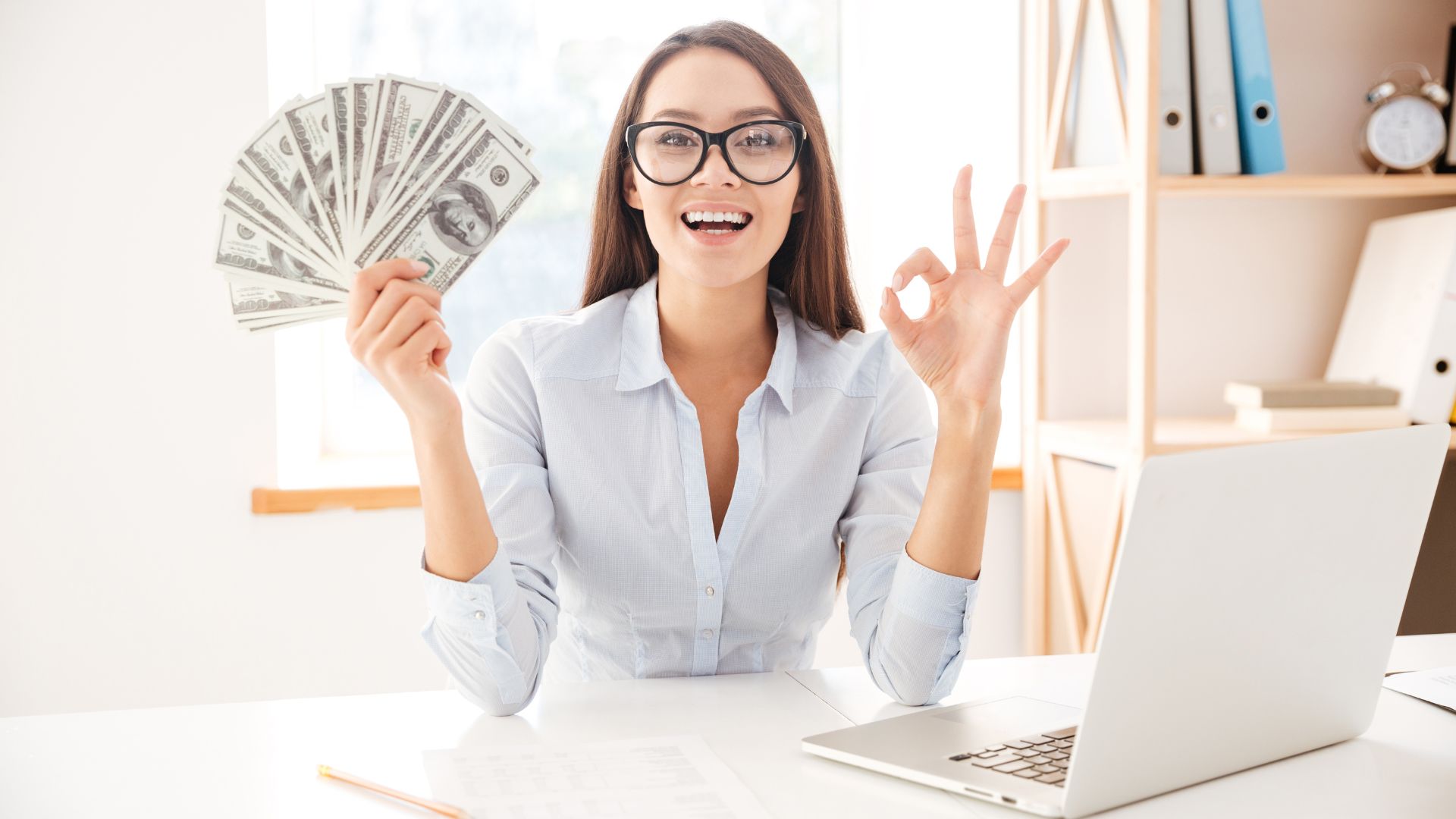 Femme heureuse avec argent faisant signe OK devant ordinateur