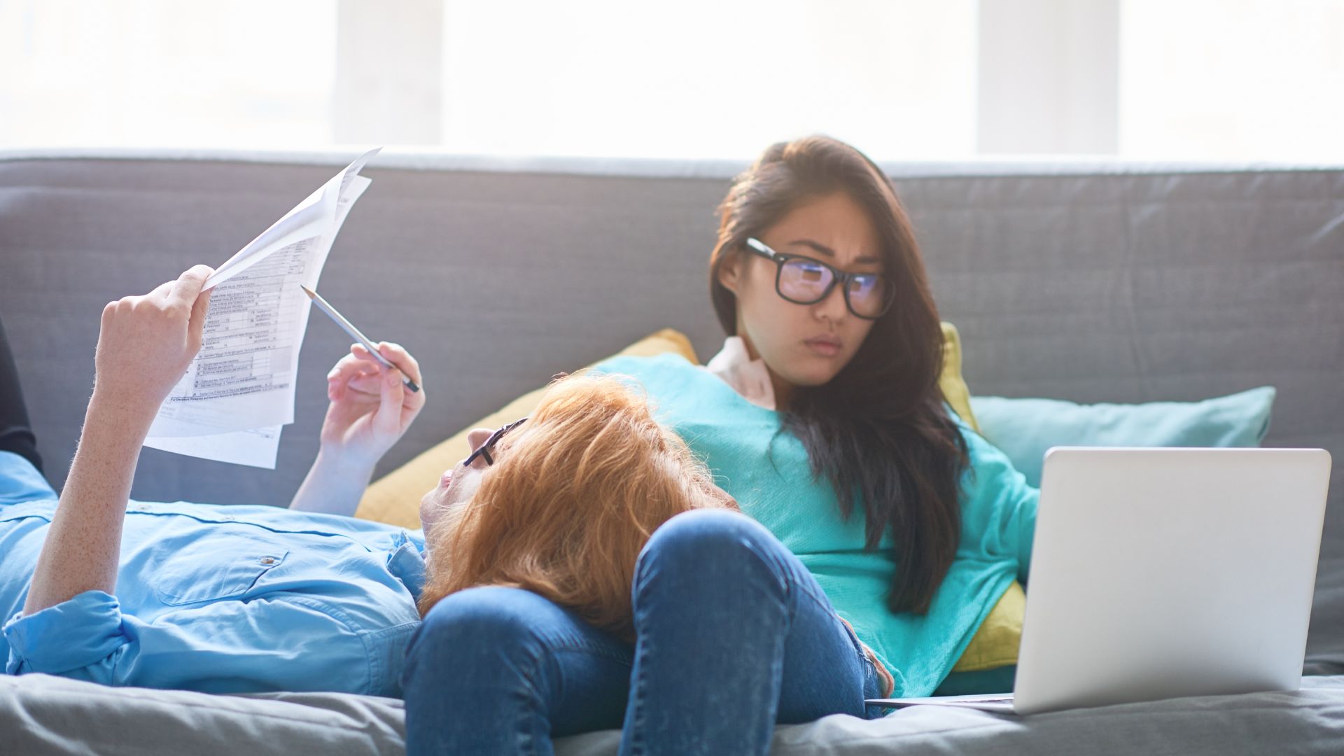 Deux femmes lisant et travaillant sur un canapé.