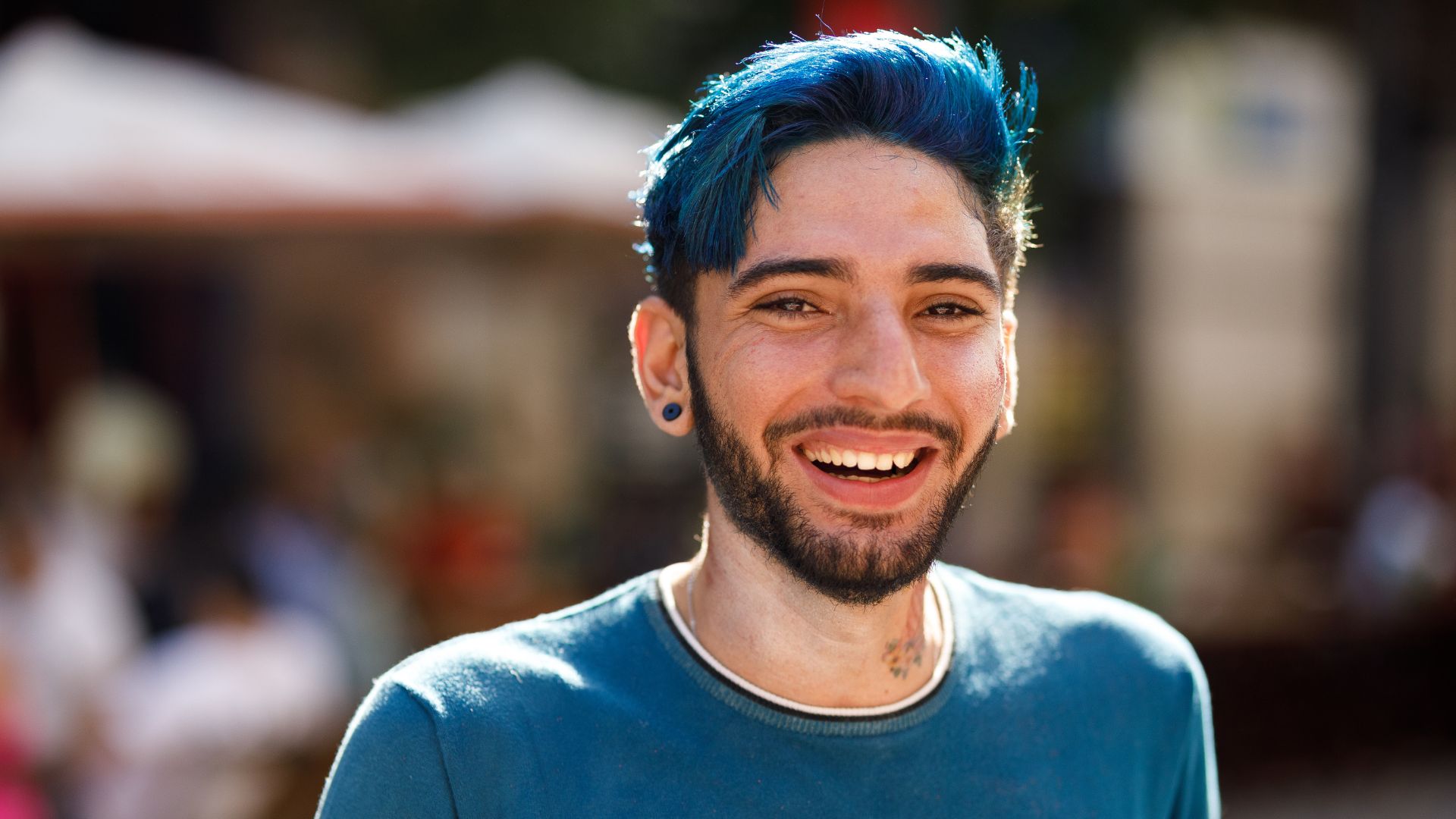 Homme souriant aux cheveux bleus.