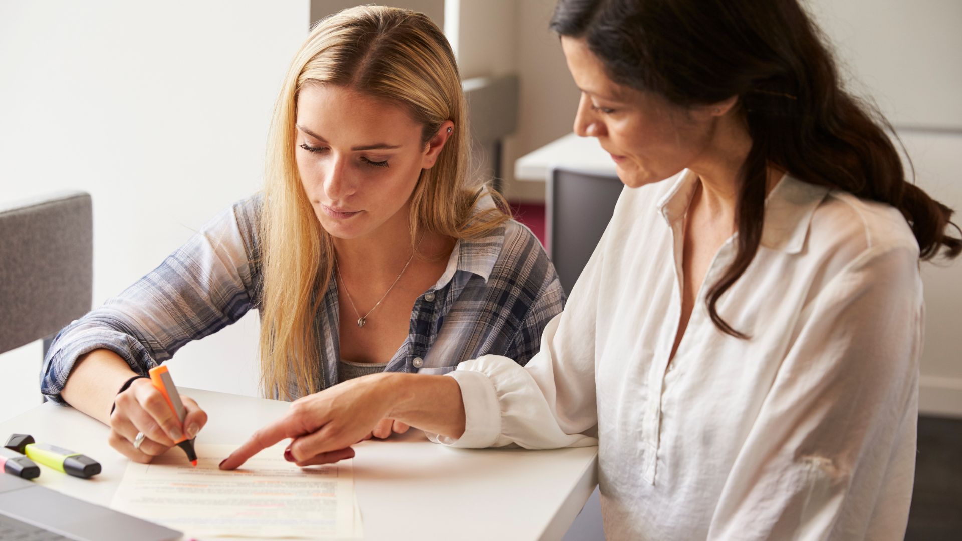 Deux femmes révisant un document ensemble.