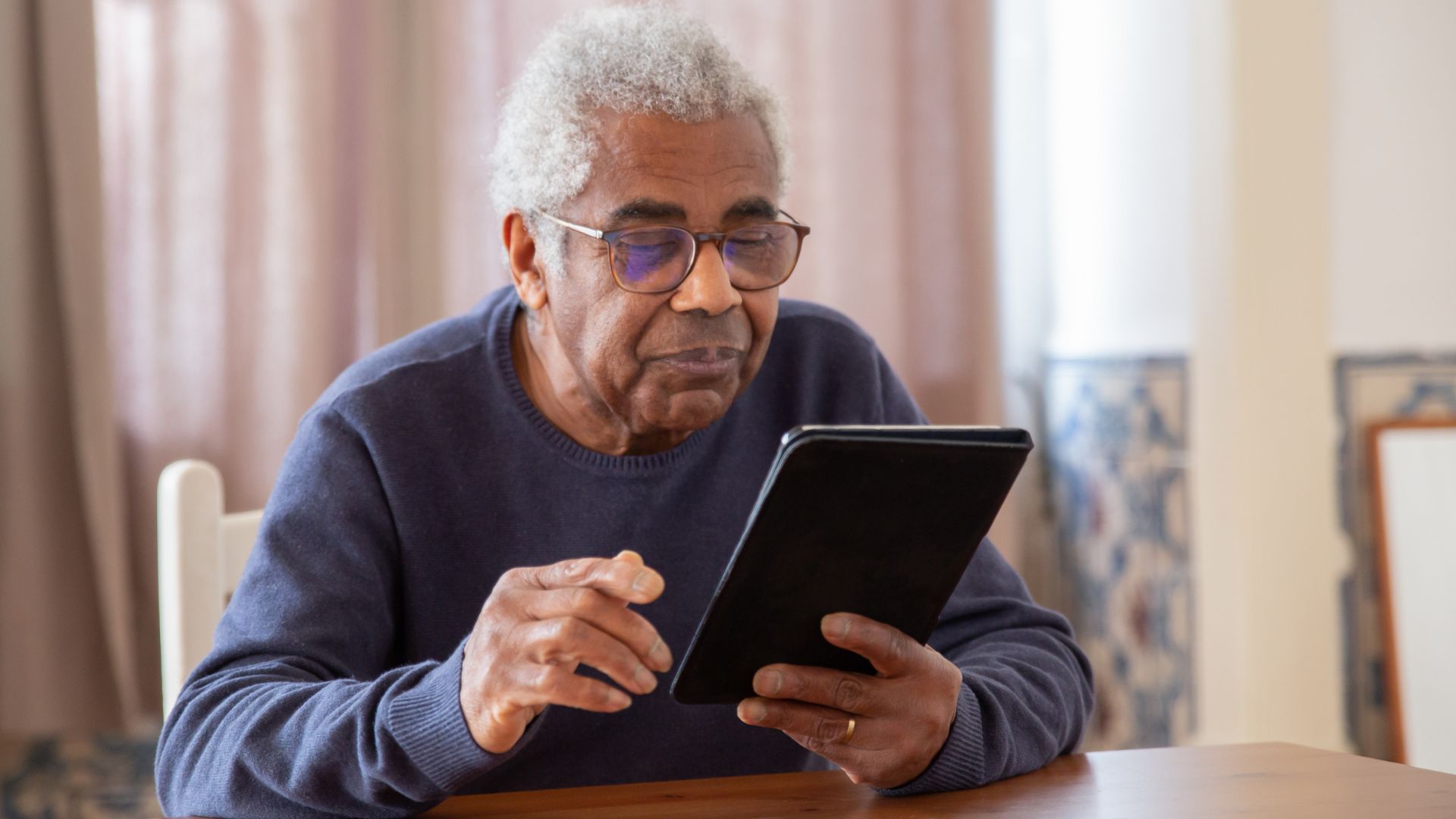 Homme âgé utilisant une tablette numérique.