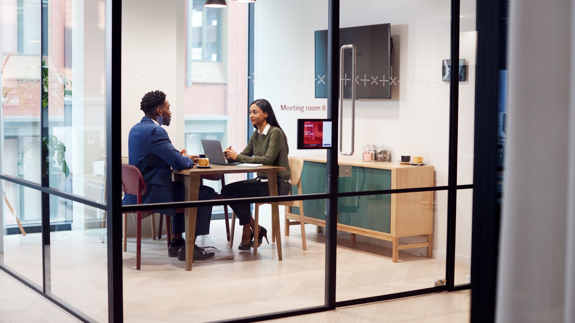 Réunion professionnelle en salle vitrée moderne.