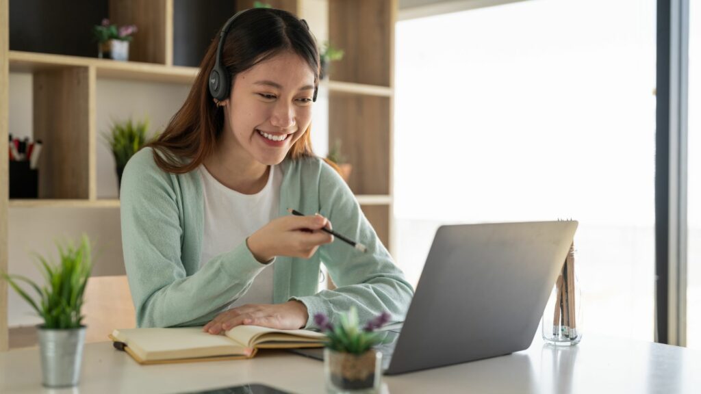 Femme souriante étudiant en ligne avec des écouteurs.
