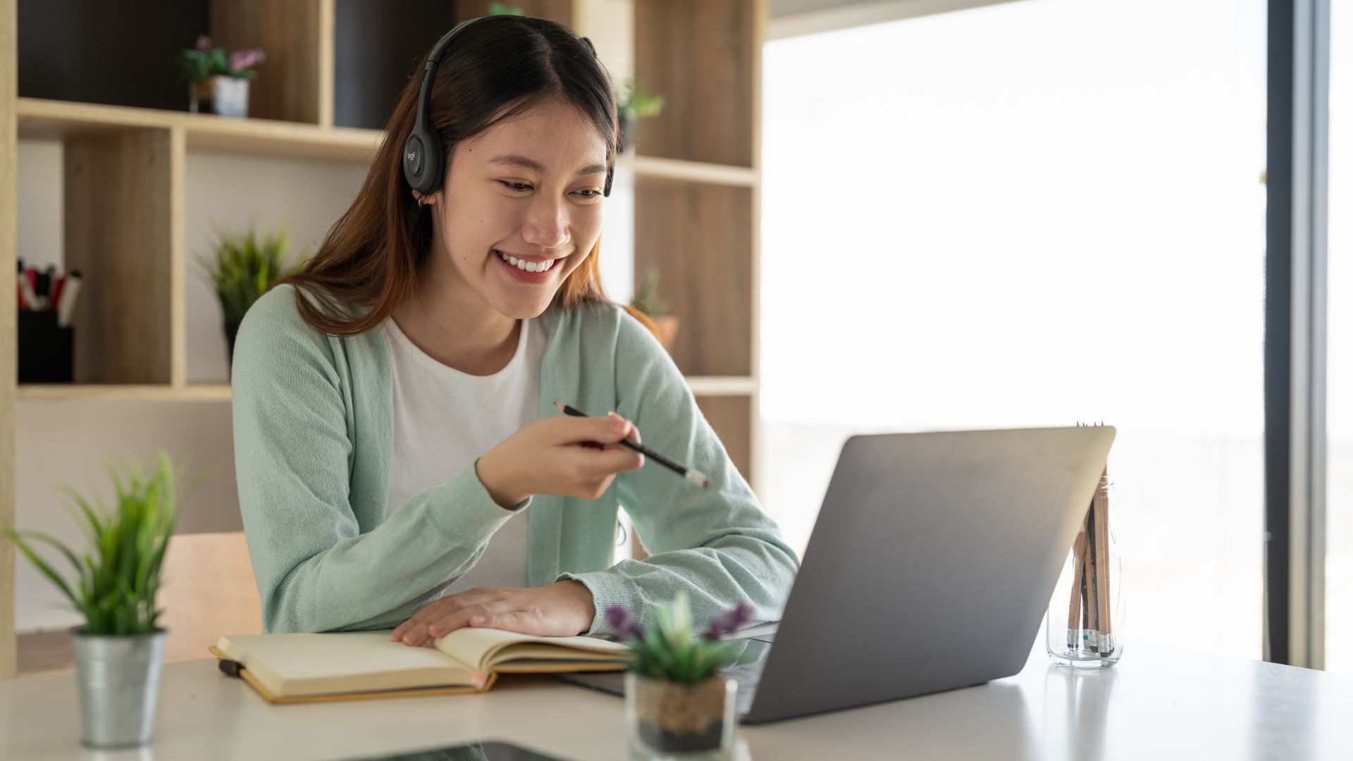 Femme souriante étudiant en ligne avec des écouteurs.