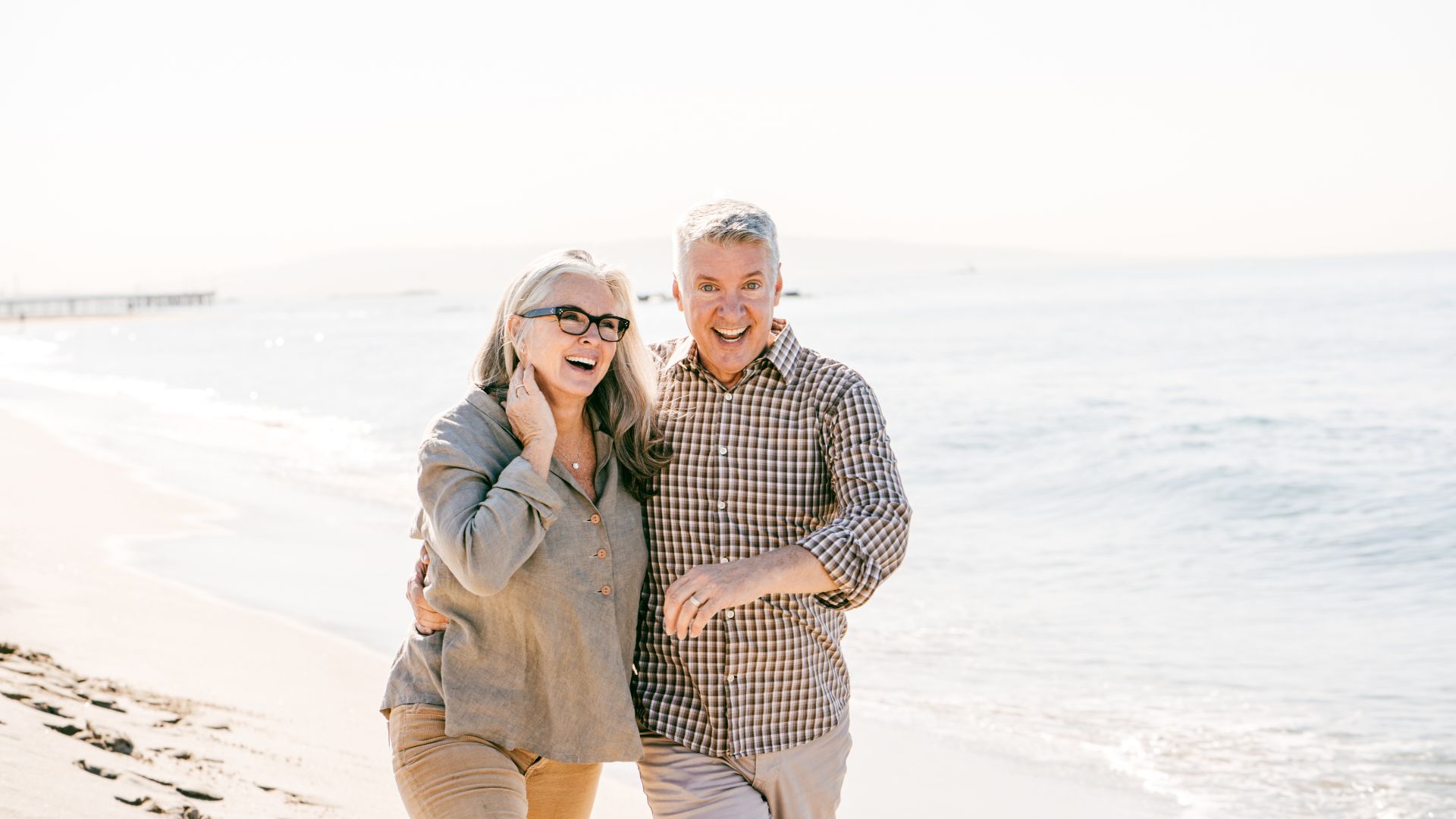 Couple âgé souriant sur la plage.