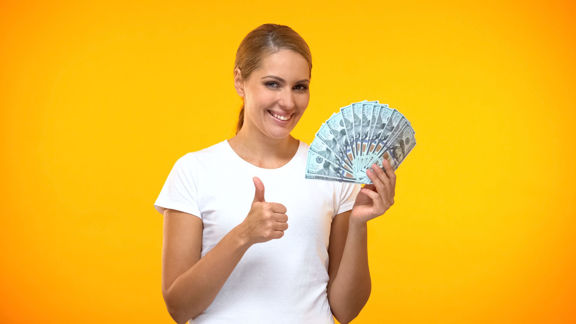 Femme souriante tenant de l'argent et faisant un pouce levé.