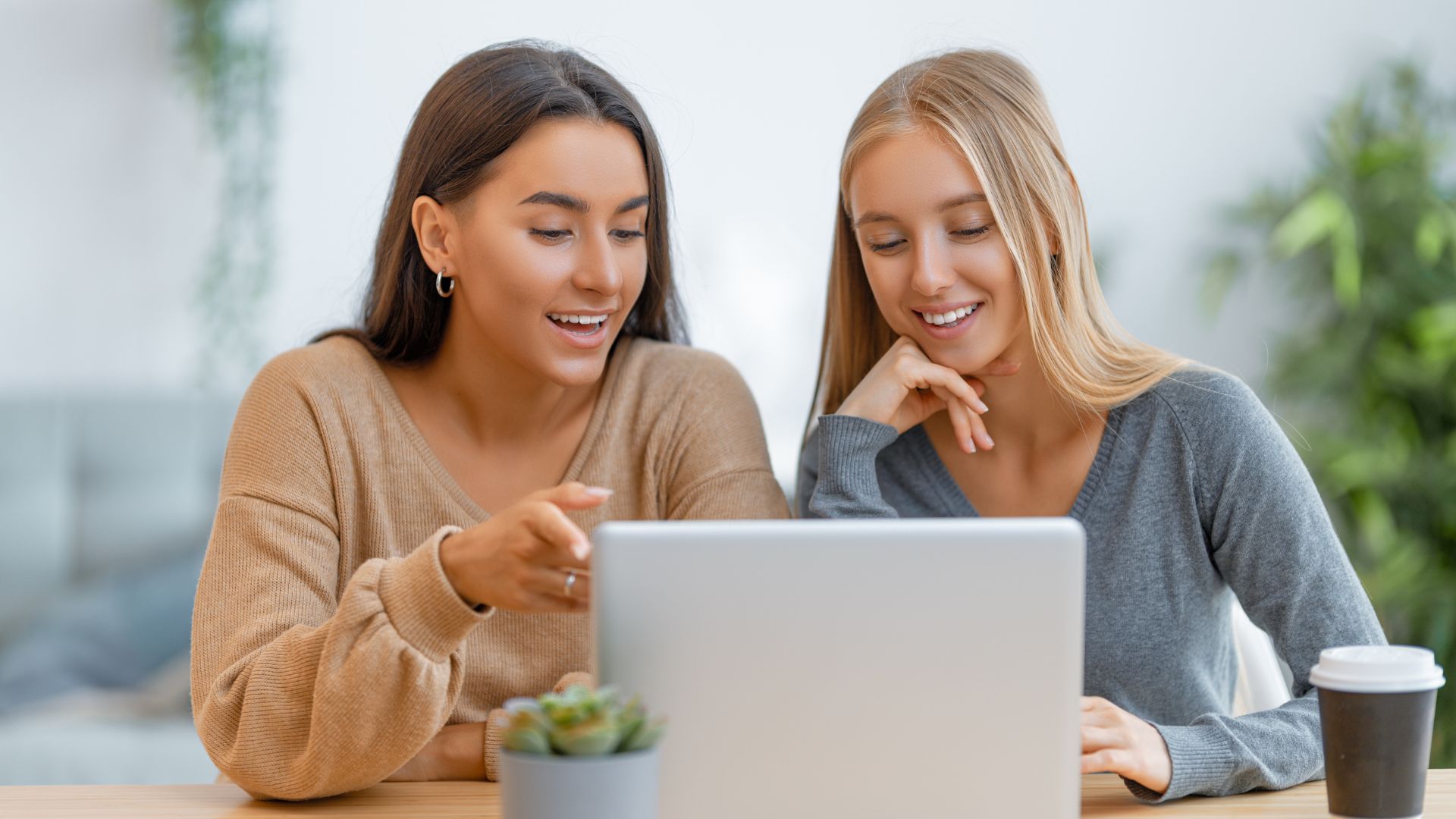 Deux femmes souriantes utilisant un ordinateur portable.
