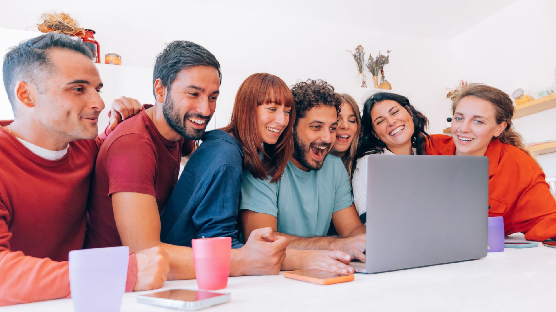 Groupe d'amis riant devant ordinateur.