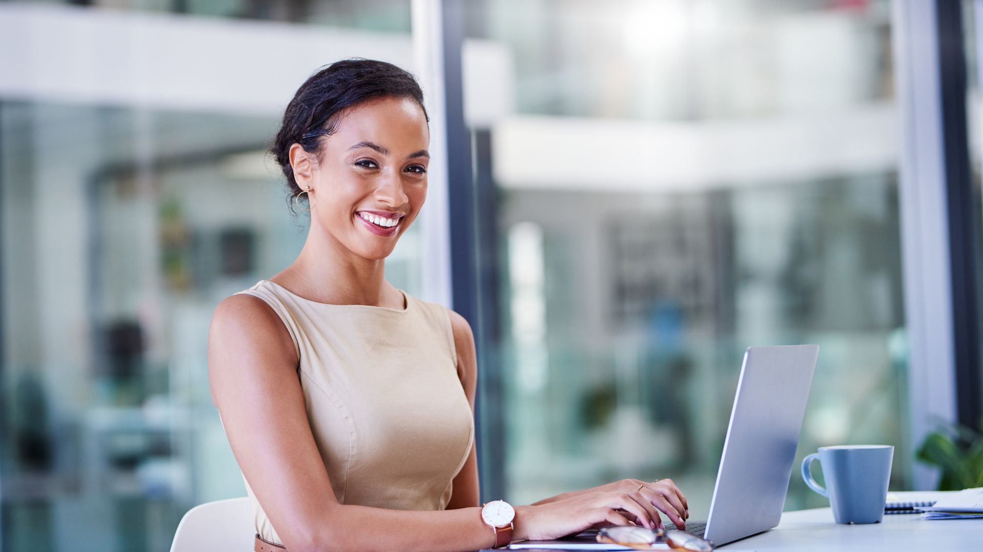 Femme souriante travaillant au bureau sur ordinateur.