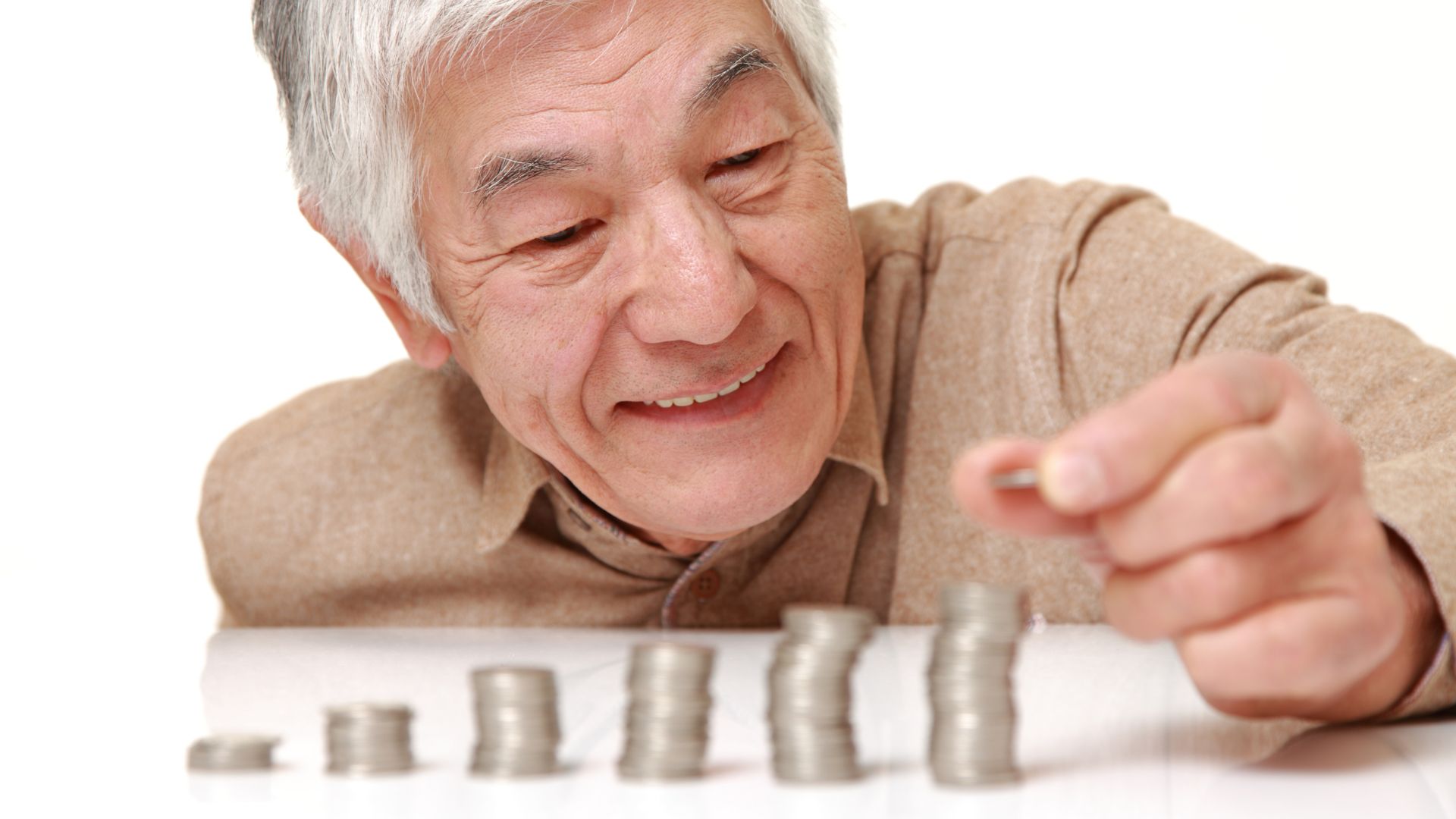 Homme âgé et piles de pièces de monnaie.