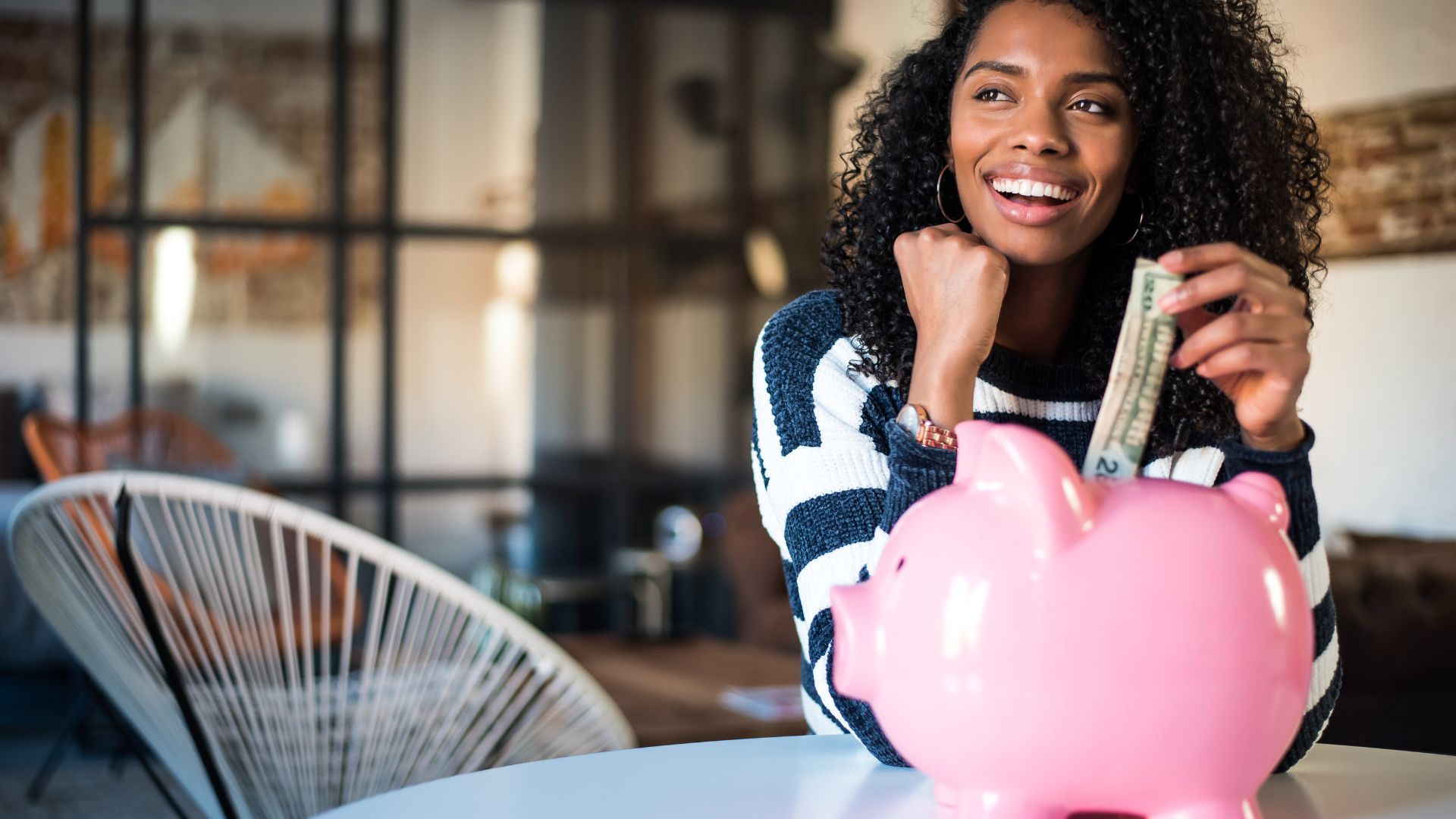 Femme souriante économisant de l'argent dans tirelire.