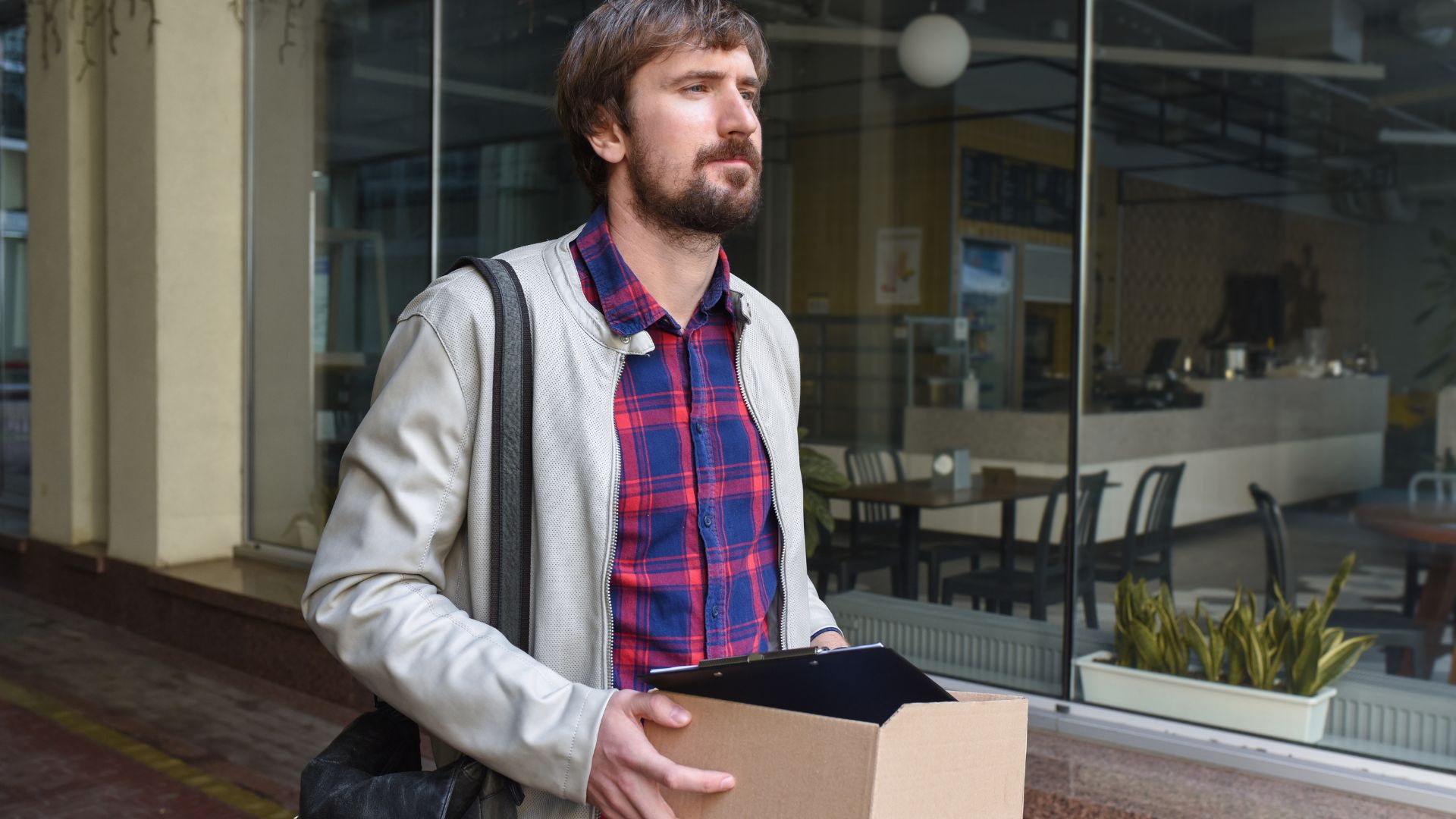 Homme portant carton devant restaurant.