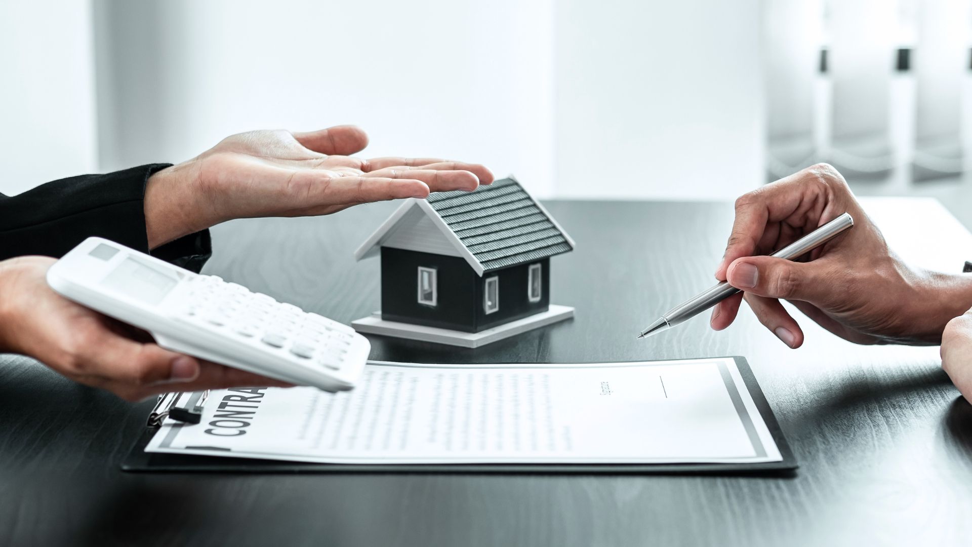 Signature de contrat immobilier avec maquette de maison.