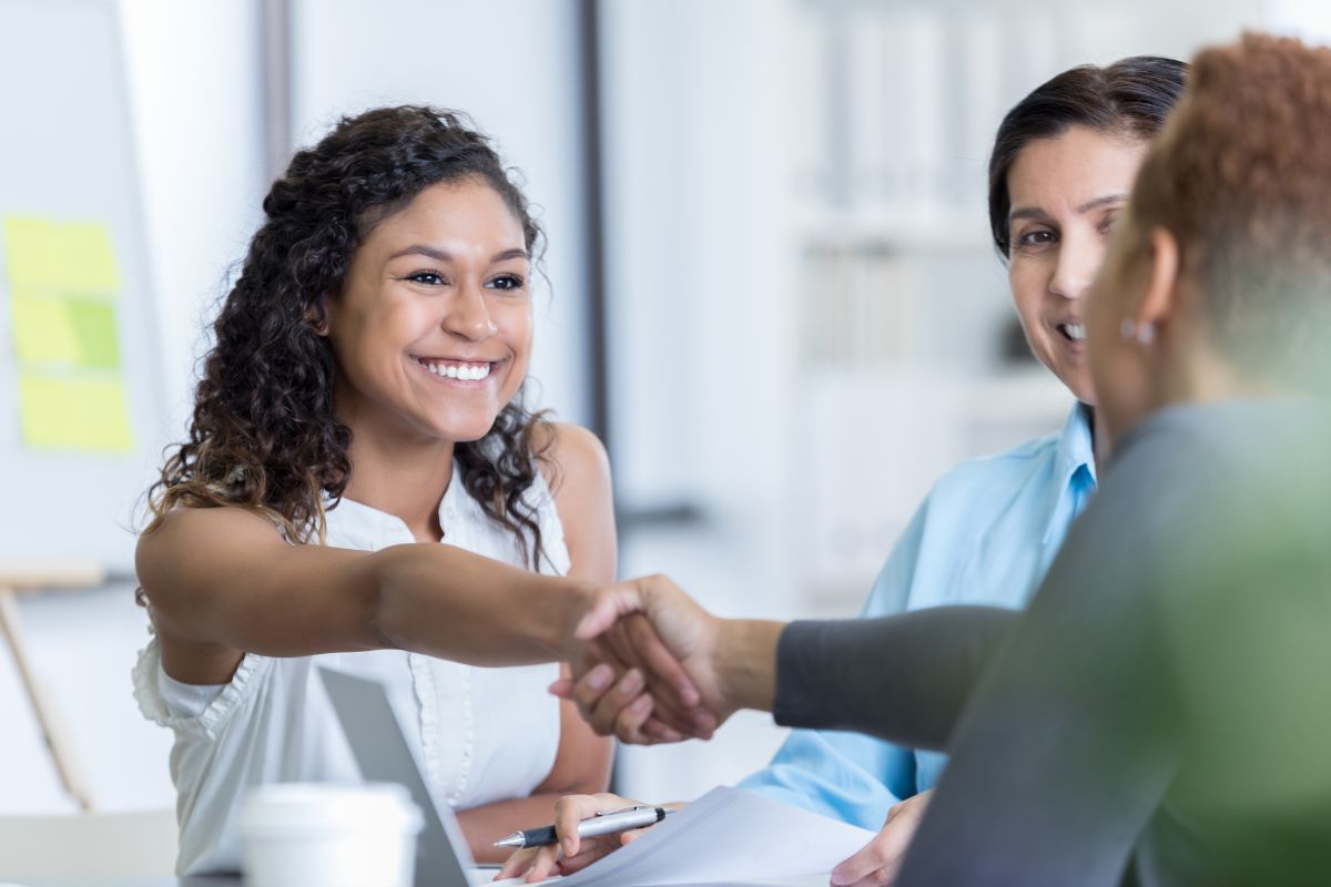 Poignée de main professionnelle entre collègues souriants.