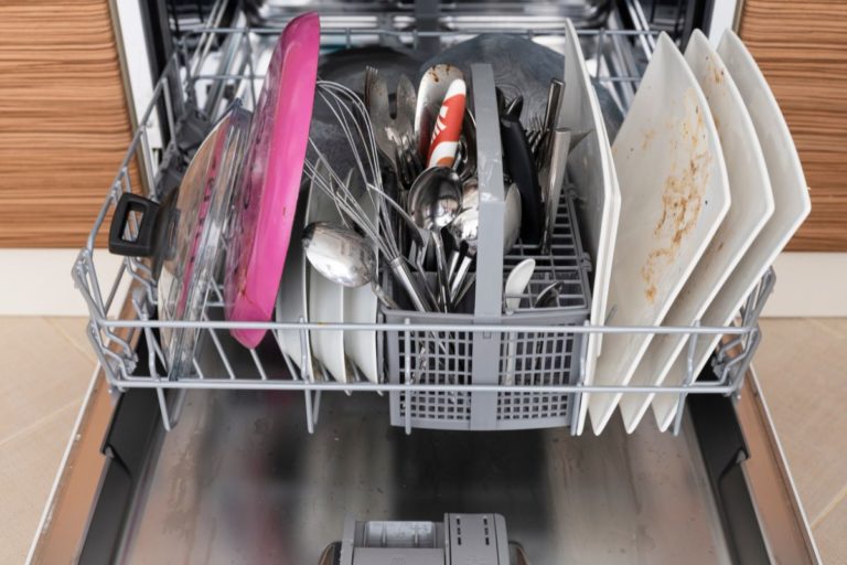 Lave-vaisselle ouvert plein de vaisselle sale.